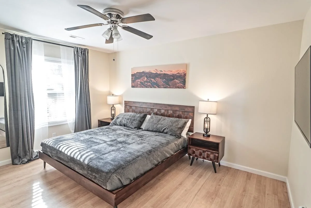 Second bedroom with wooden bed frame, nightstands and mountain artwork