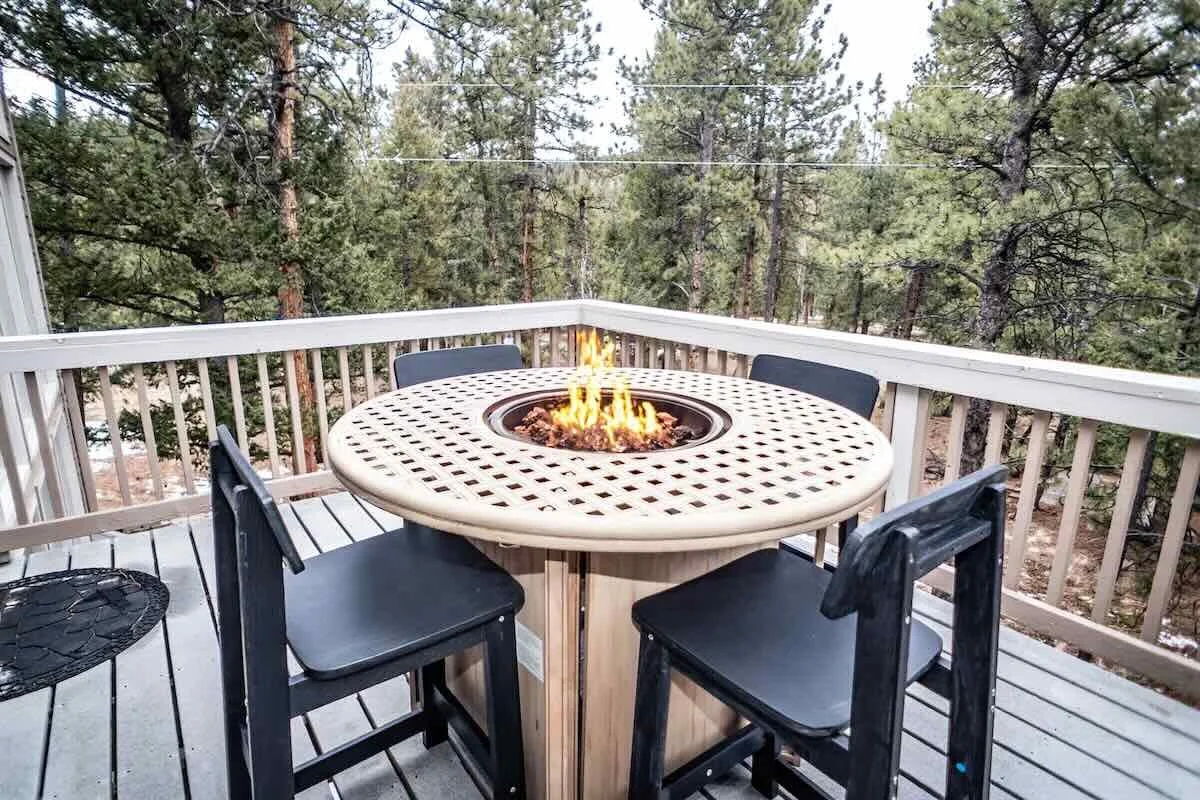 Round fire table and four chairs on the upper deck above the forest