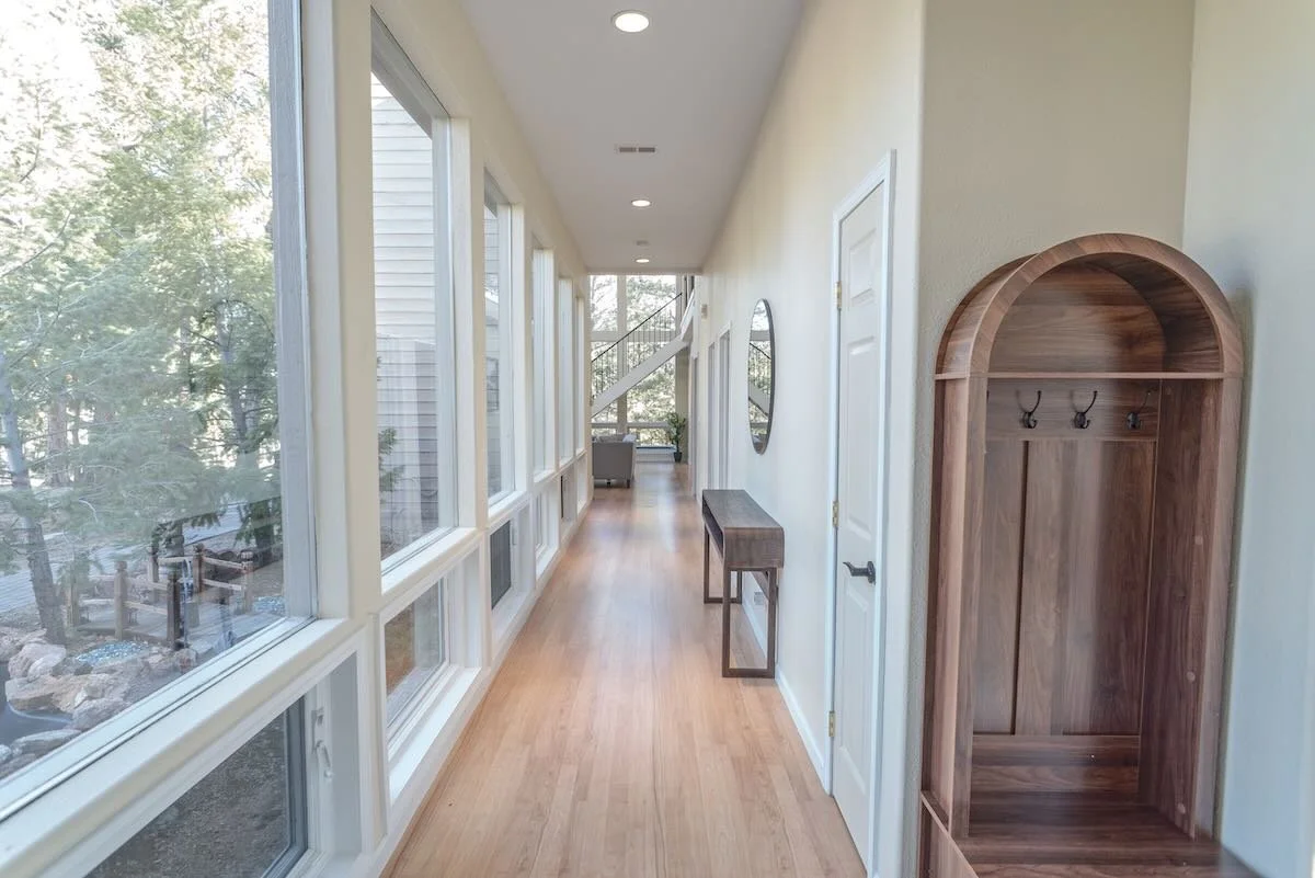 Bright entry hallway with windows on one side and coat hooks on the other