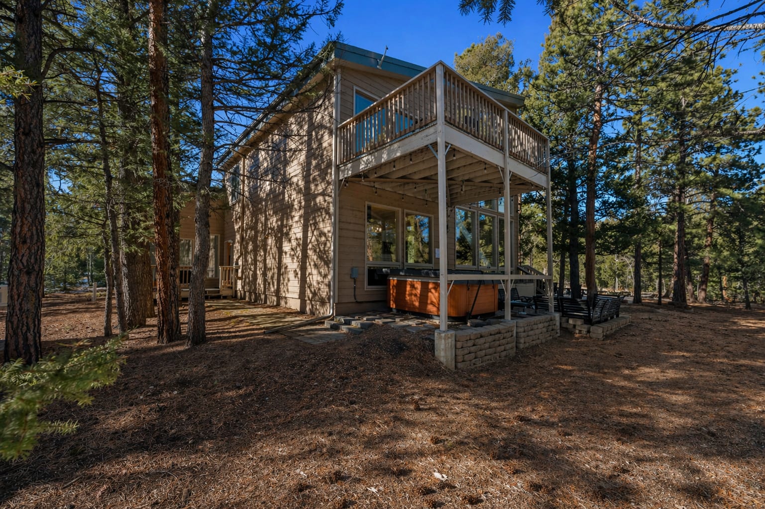 Rear exterior with private upper deck, covered hot tub and forest views
