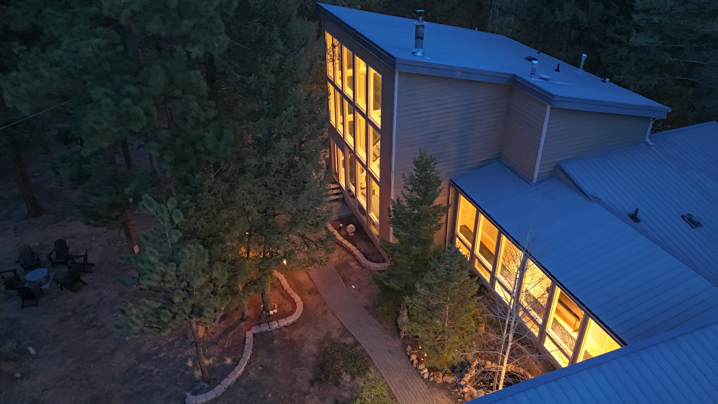 Daytime exterior of The Stillwood Retreat surrounded by tall pine trees