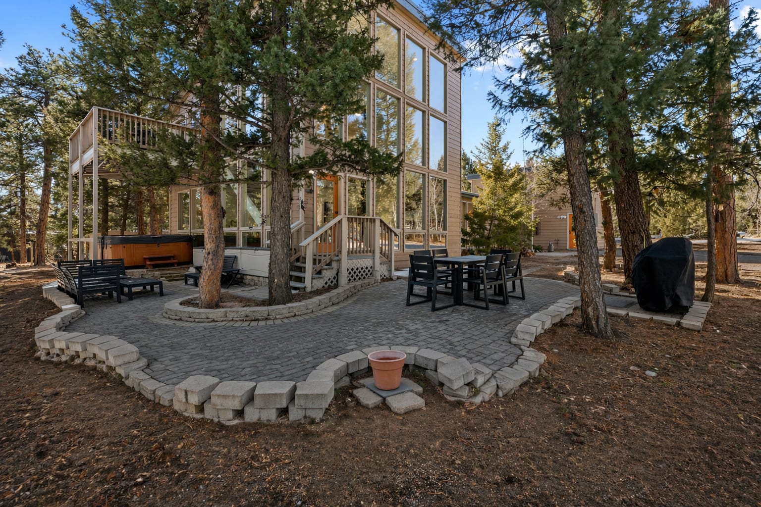 Glass-walled rear exterior with hot tub, patio lounge and outdoor dining