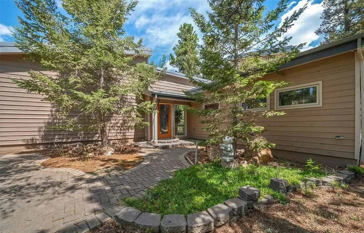 Front entry with brick patio surrounded by trees and landscaping