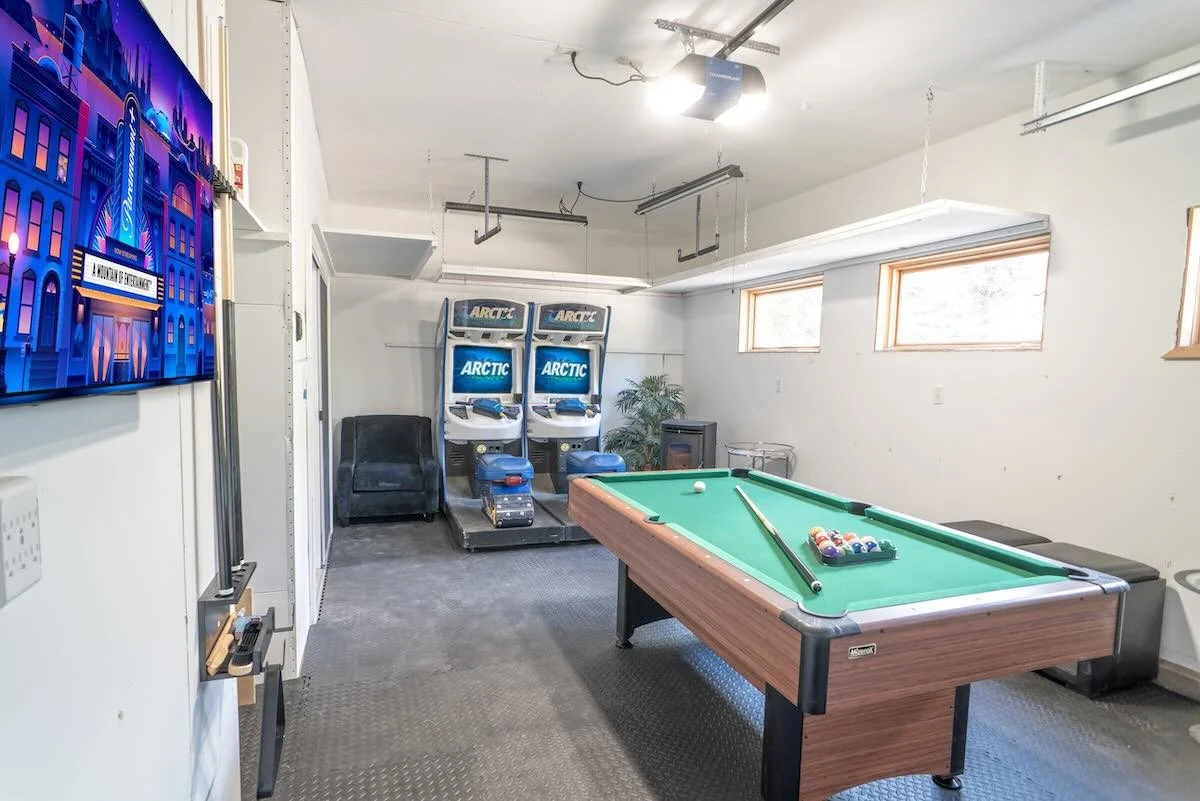 Game room with pool table, arcade machines and a wall-mounted TV