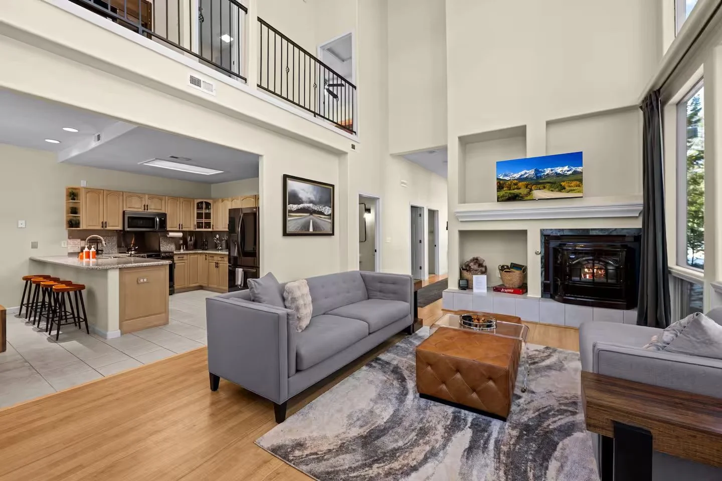 Living room with L-shaped sofa and ottoman adjoining the open kitchen