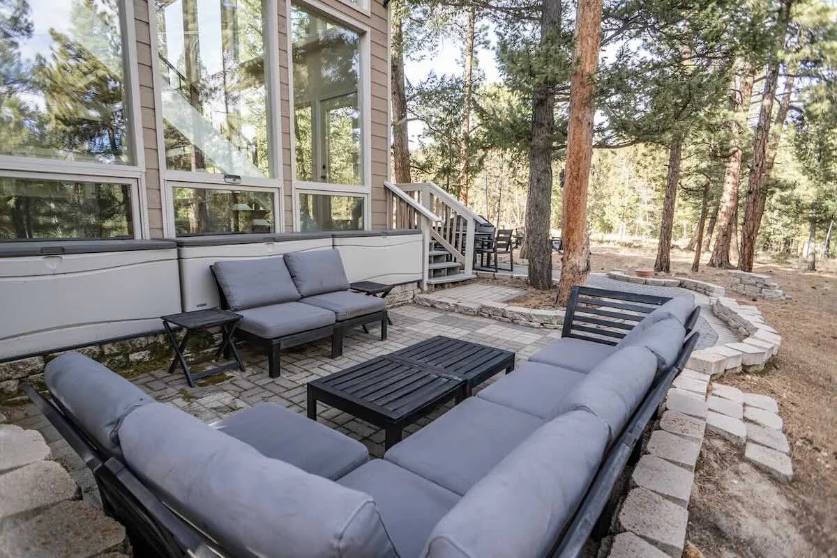 Patio sectional and chairs backed by forest