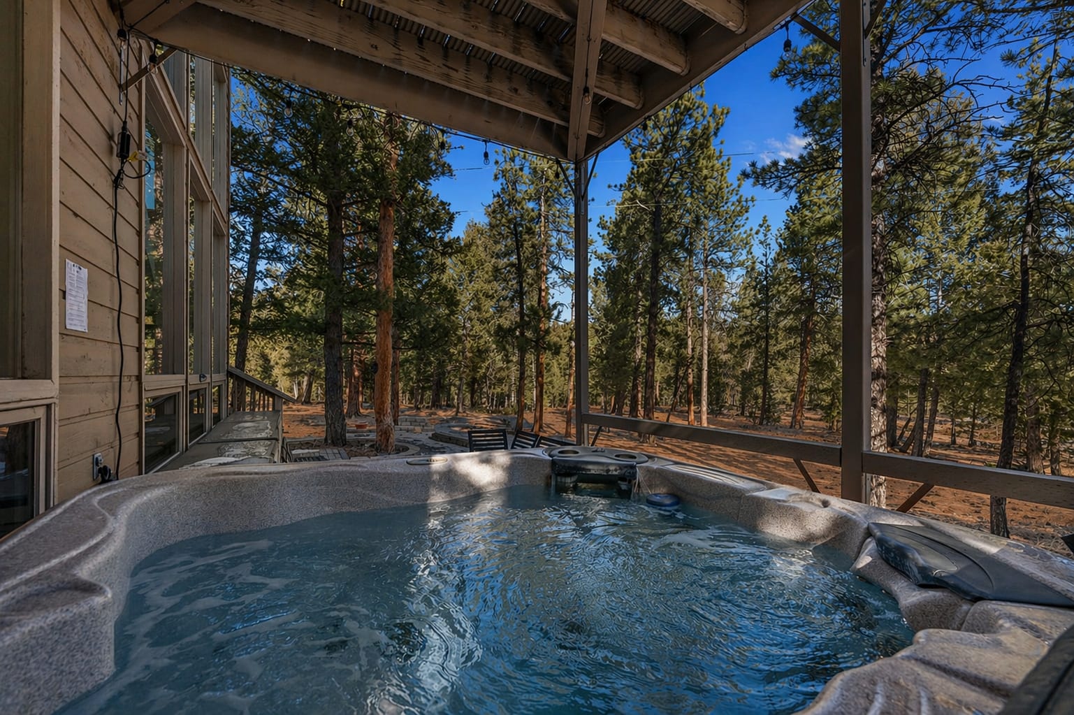 Private hot tub under the deck overlooking the surrounding pine forest