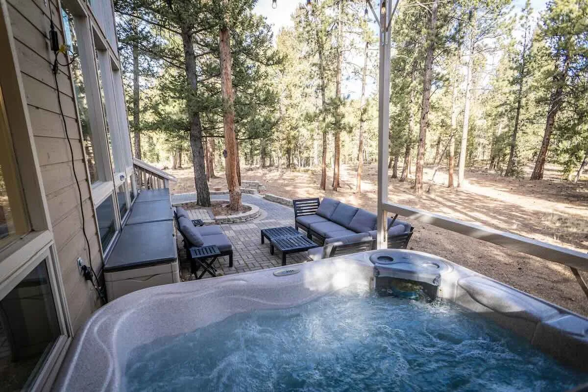 Patio with hot tub and lounge seating overlooking the forest