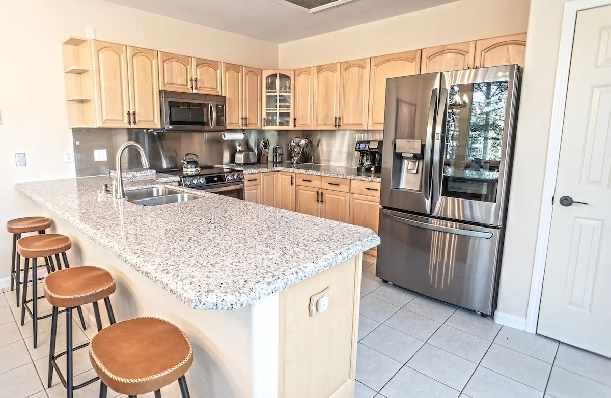 Kitchen with granite counters, stainless appliances and a breakfast bar with four stools