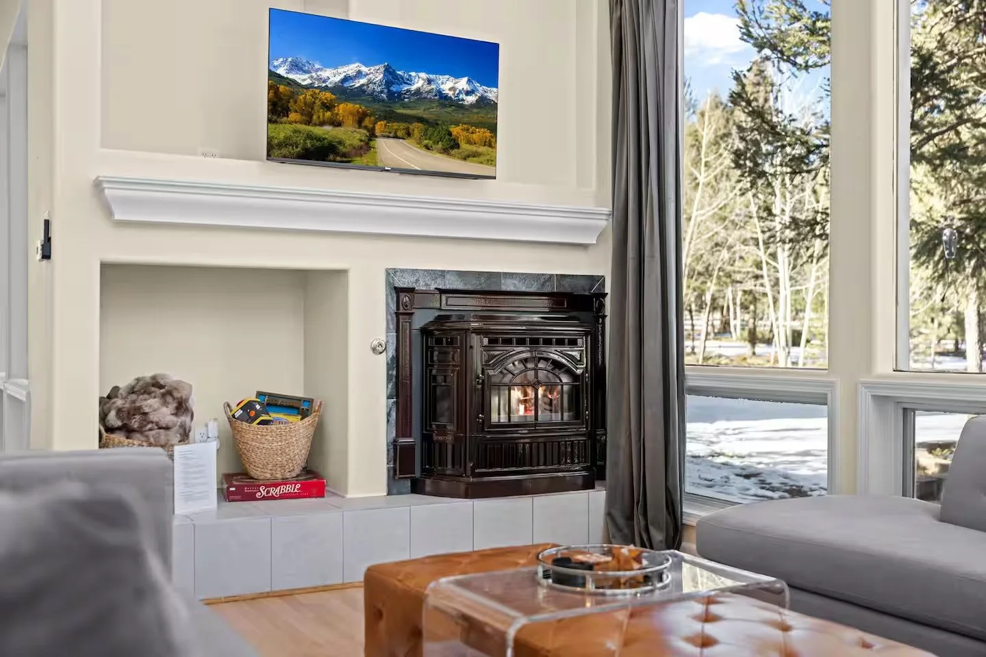 Living room fireplace with large windows showing a snowy scene outside