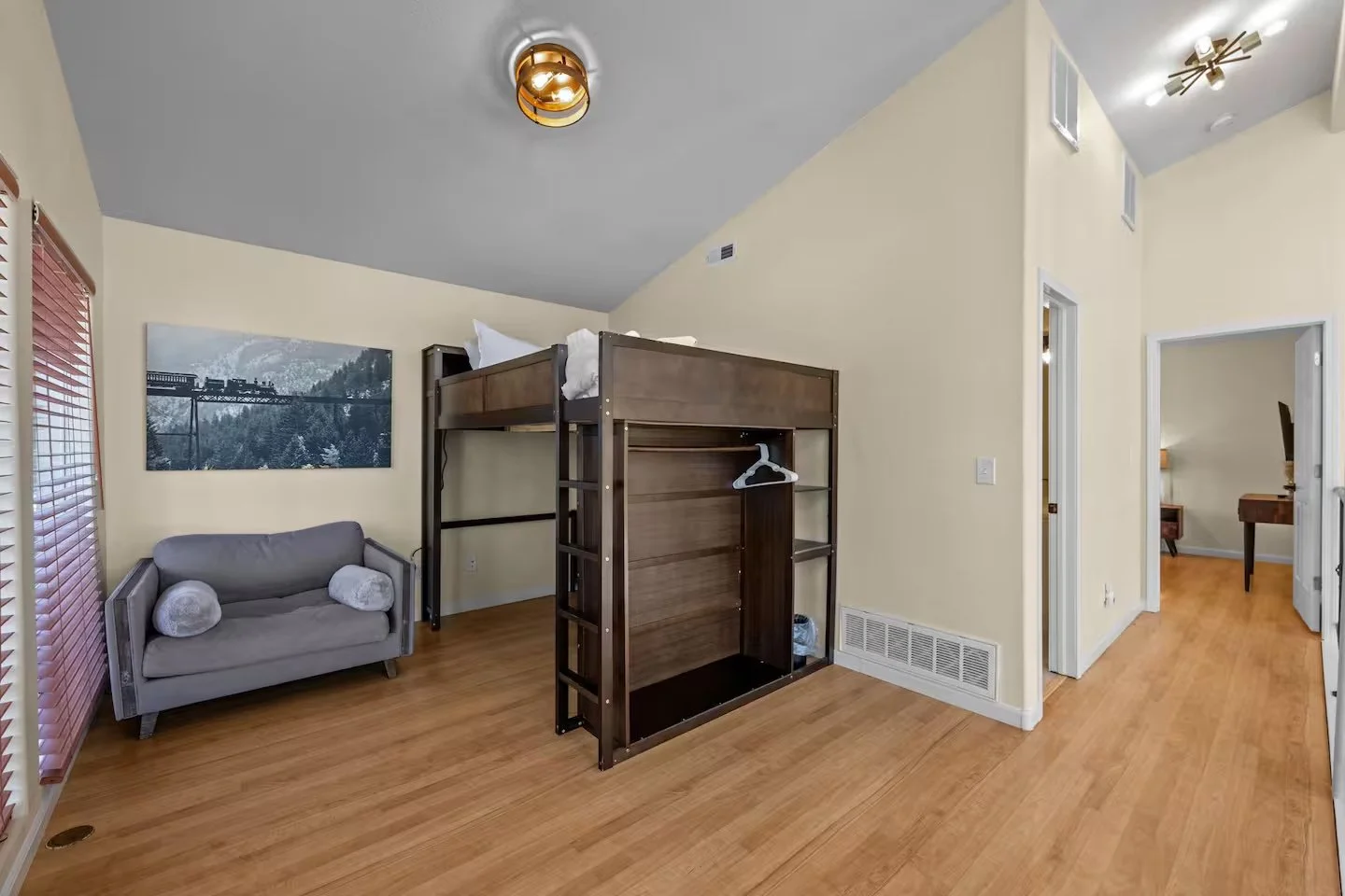 Loft room with lofted bed, small sofa and sliding glass door