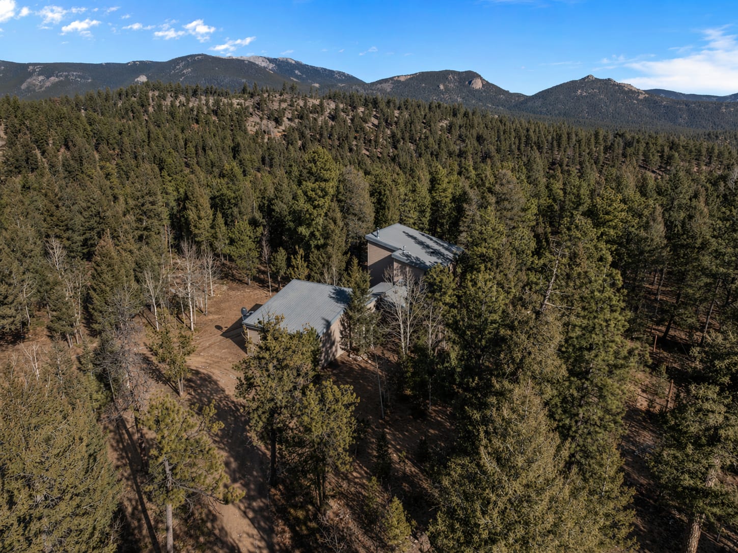 Aerial view of The Stillwood Retreat surrounded by forest with mountains beyond