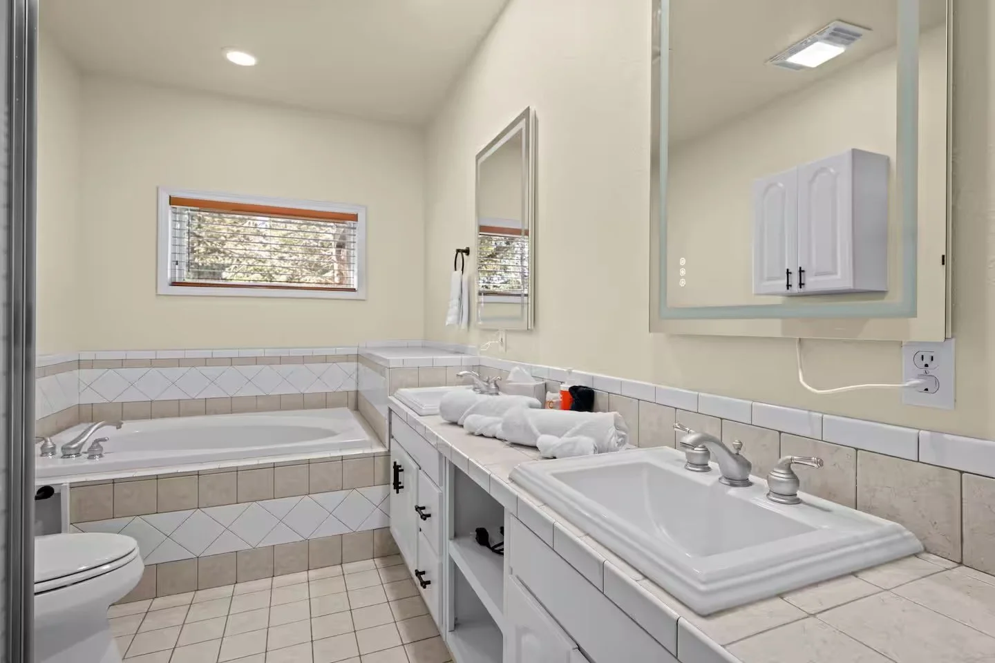 Bathroom with bathtub, double sinks and window